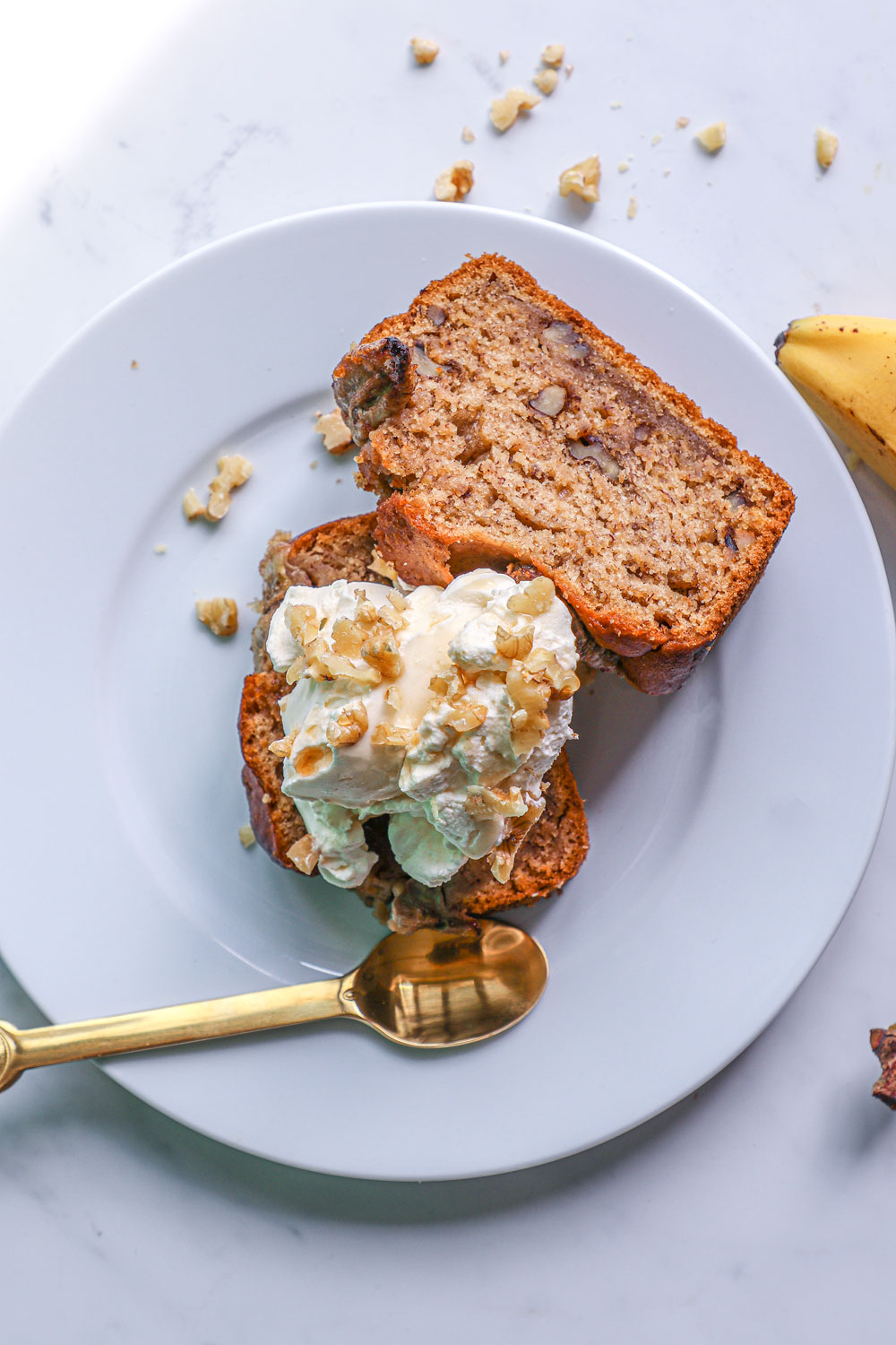 banana and walnut bread loaf slices topped with whipped cream , chopped walnuts and a drizzle of maple syrup