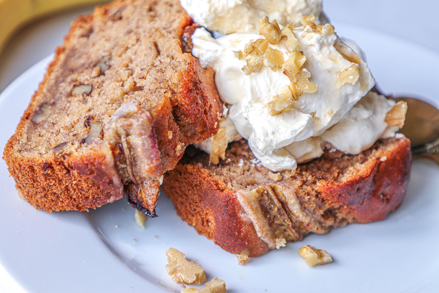 banana and walnut bread loaf slices topped with whipped cream , chopped walnuts and a drizzle of maple syrup