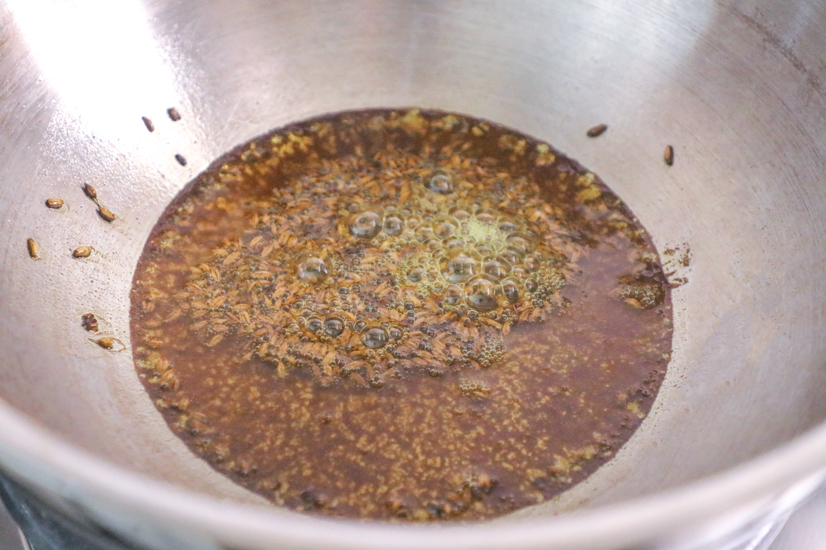 Heating Cumin seeds in hot oil in a stainless steel karahi