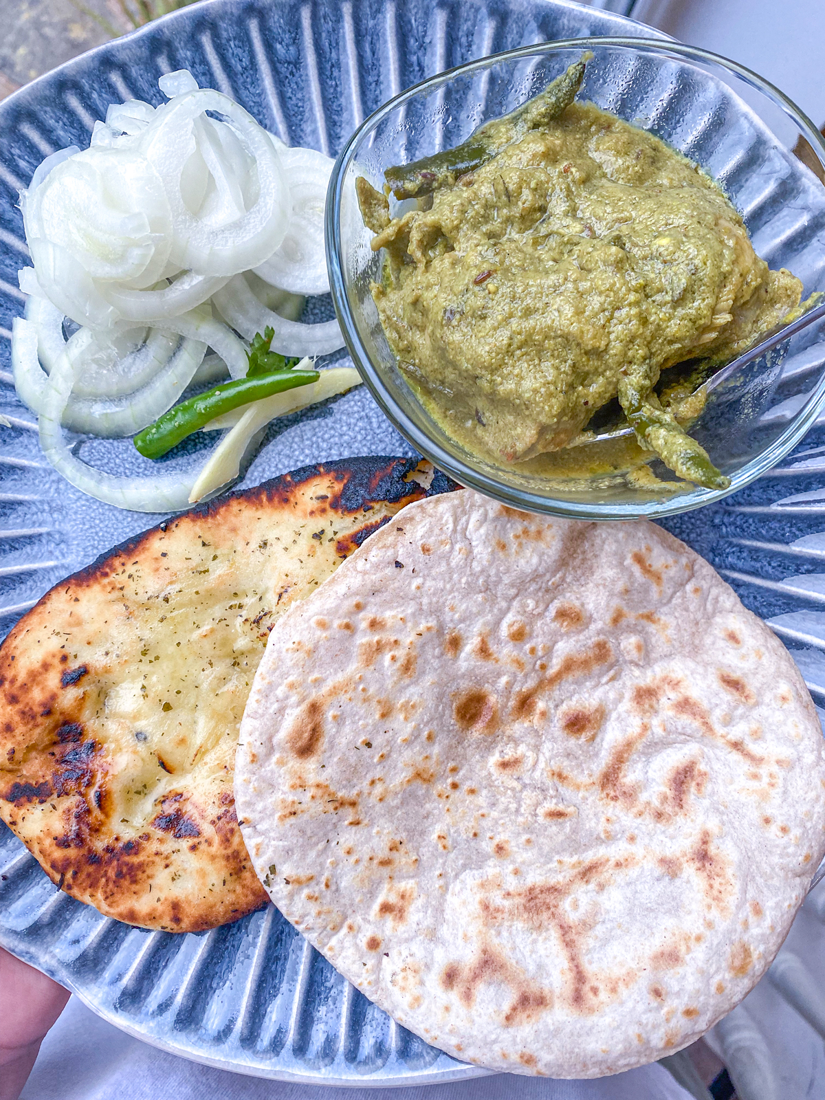 Green chilli chicken Roti naan onion salad served on a blue ribbed plate
