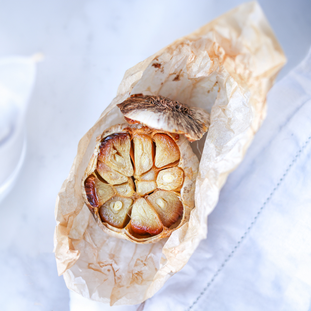 Roasted garlic in the parchment paper on white background